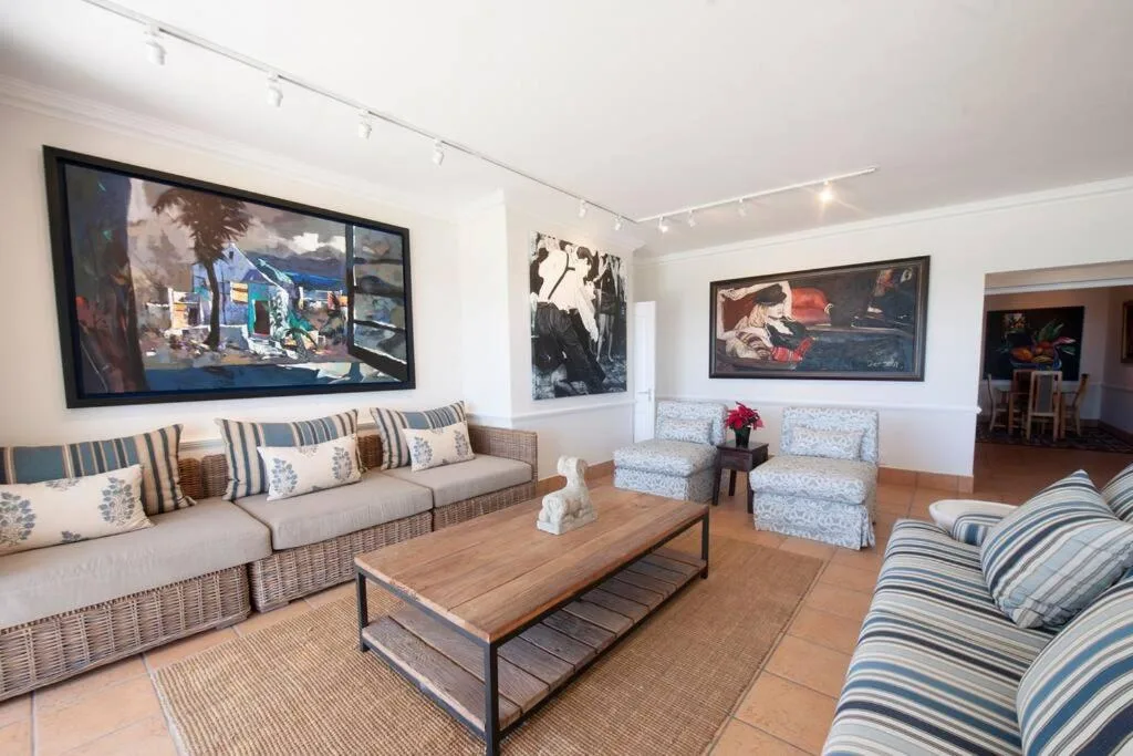 Spacious lounge with striped sofas, wooden coffee table, and framed artwork