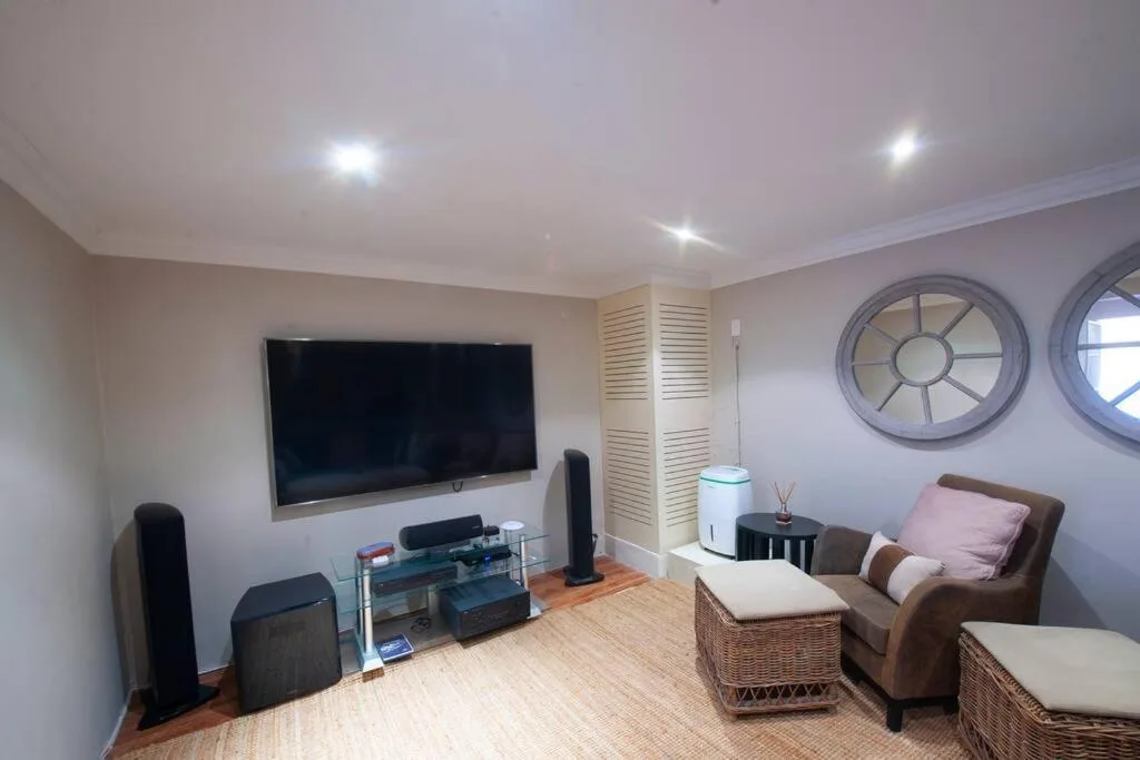 Spacious living room with wall-mounted TV, brown leather armchair, and decorative round windows