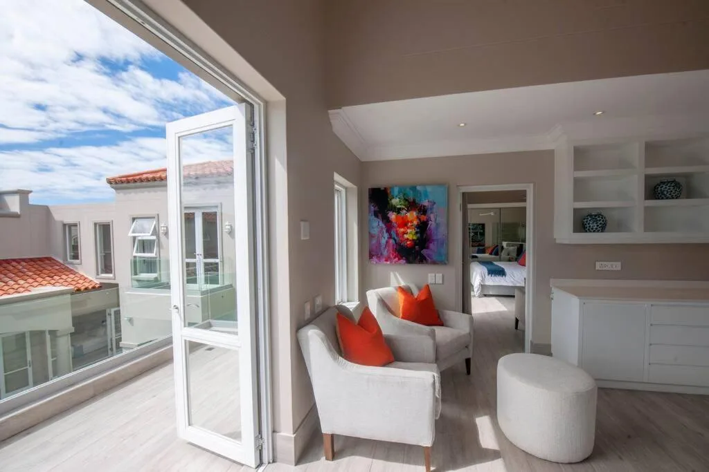 Modern lounge with white armchairs, colorful artwork, and ocean view access