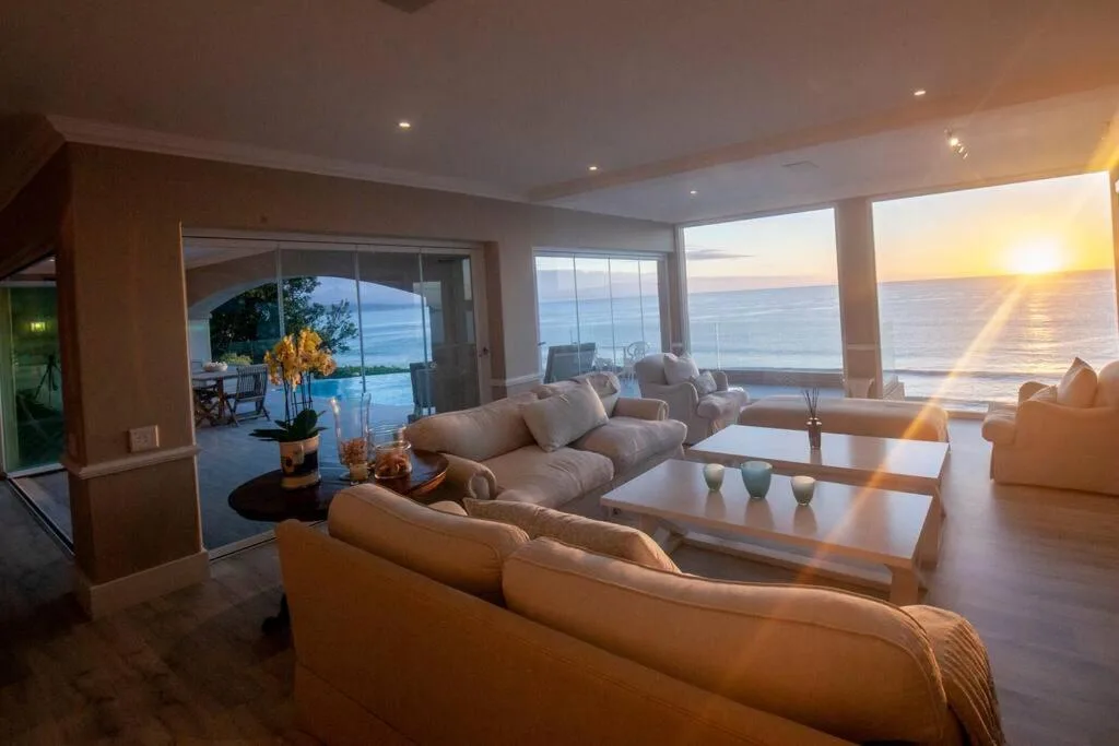Spacious lounge with cream sofas overlooking ocean sunset views