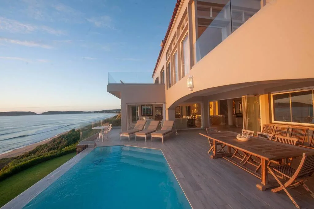 Swimming pool with ocean and mountain views at sunset