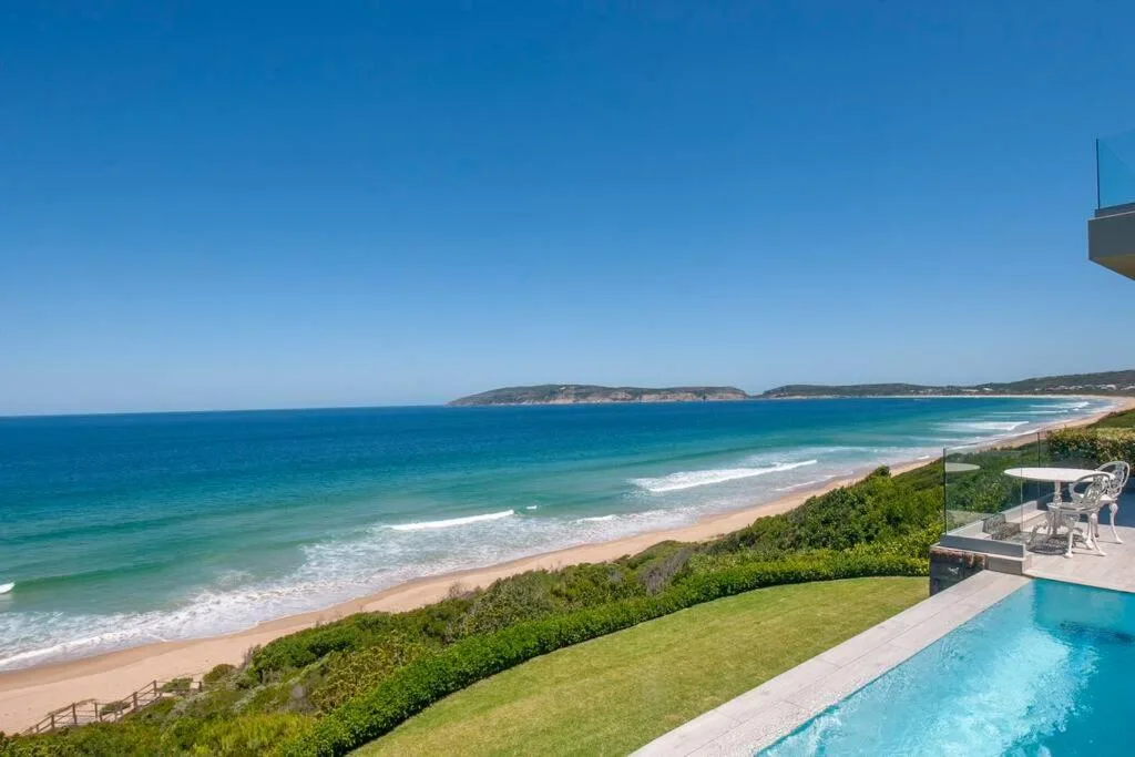 Turquoise ocean and sandy beach stretching along pristine coastline under blue sky