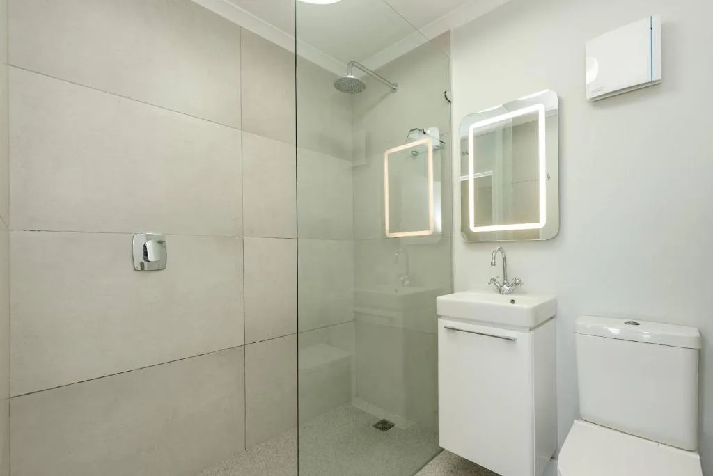 Modern bathroom with walk-in shower, white vanity, and illuminated mirrors