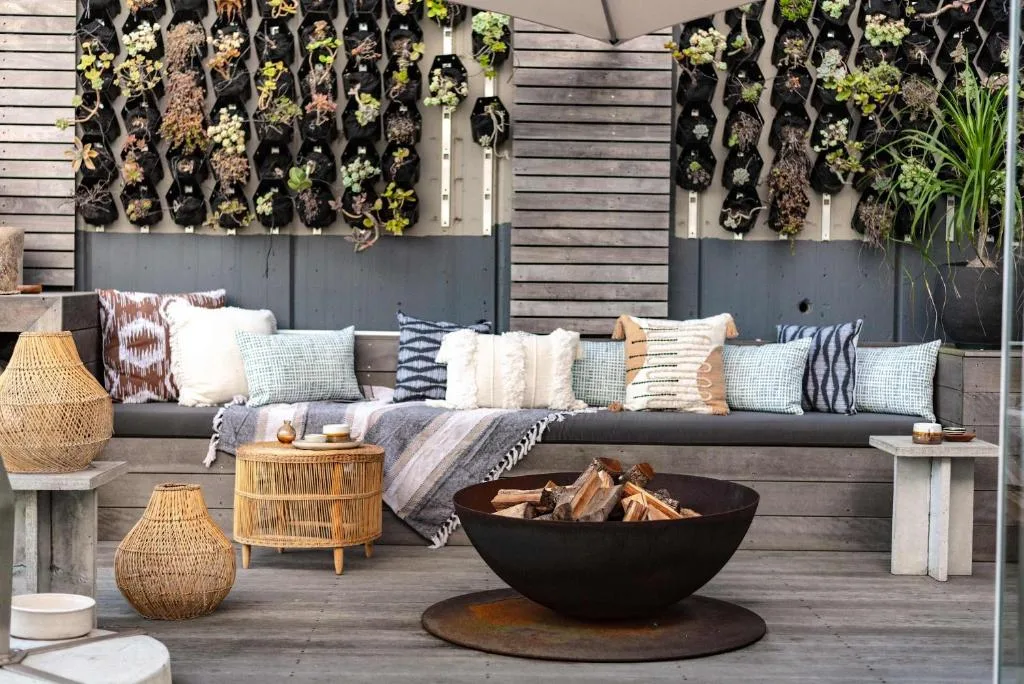 Outdoor seating area with cushioned bench, fire pit, and vertical plant wall