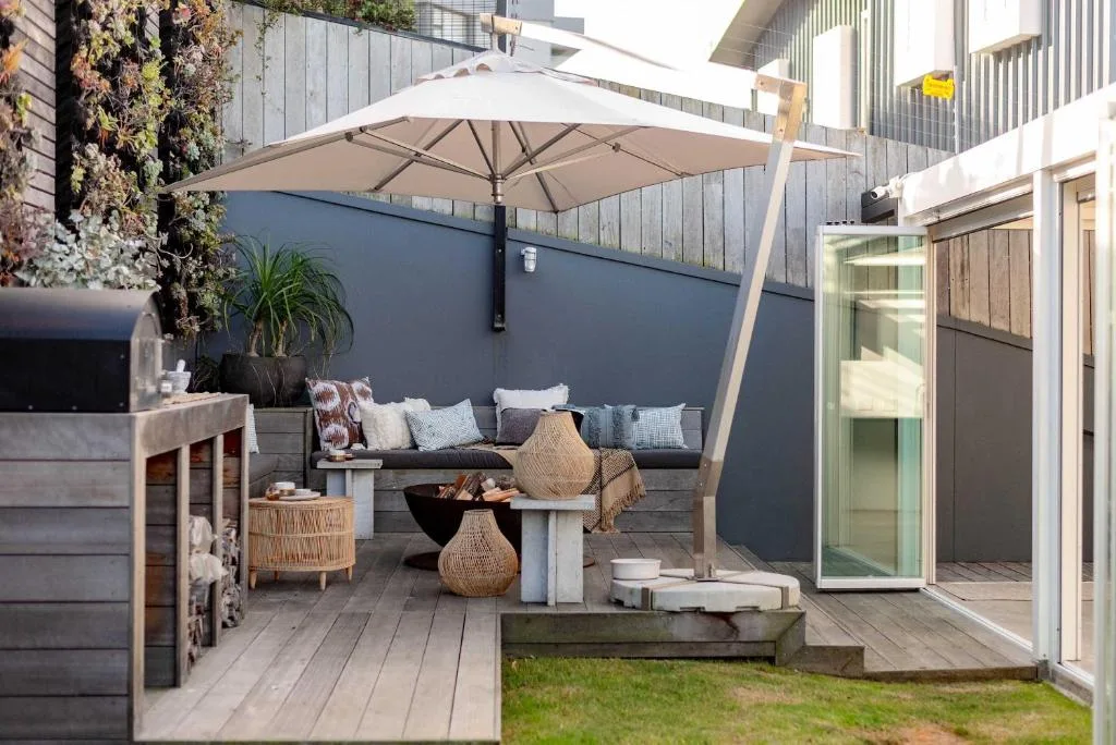 Shaded outdoor patio with lounge seating, umbrella, and fire pit area