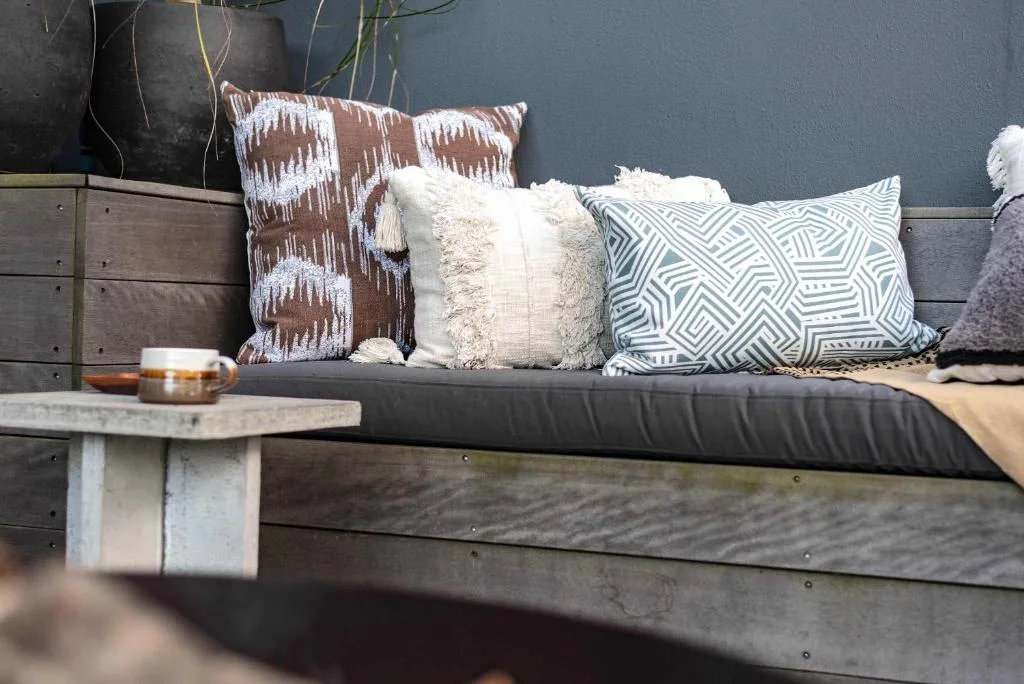 Outdoor seating area with decorative pillows and cushions on wooden bench