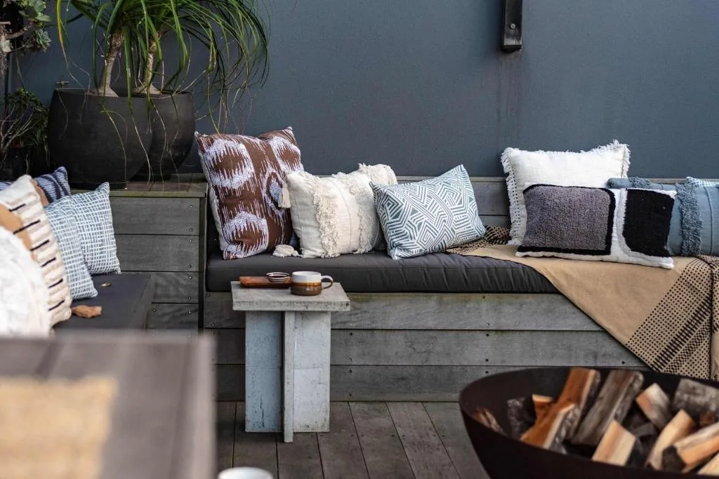 Outdoor wooden seating area with patterned cushions and potted plants