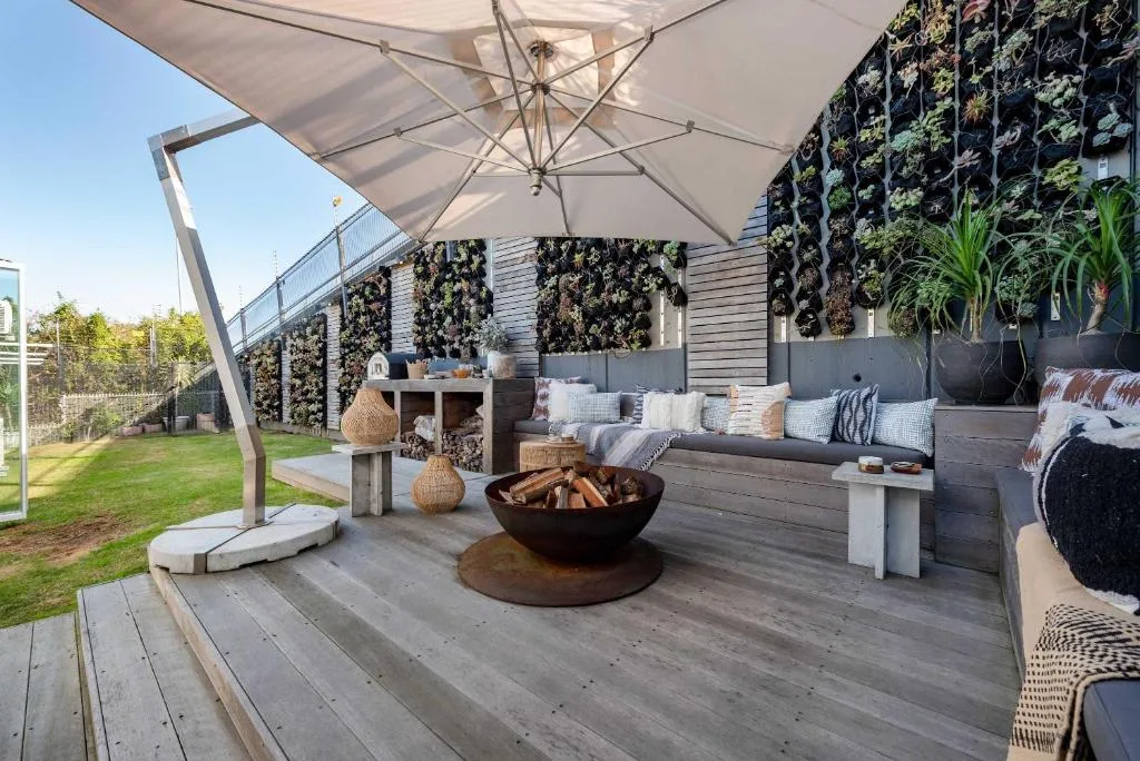 Modern outdoor deck with built-in seating, fire bowl, umbrella, and living green walls