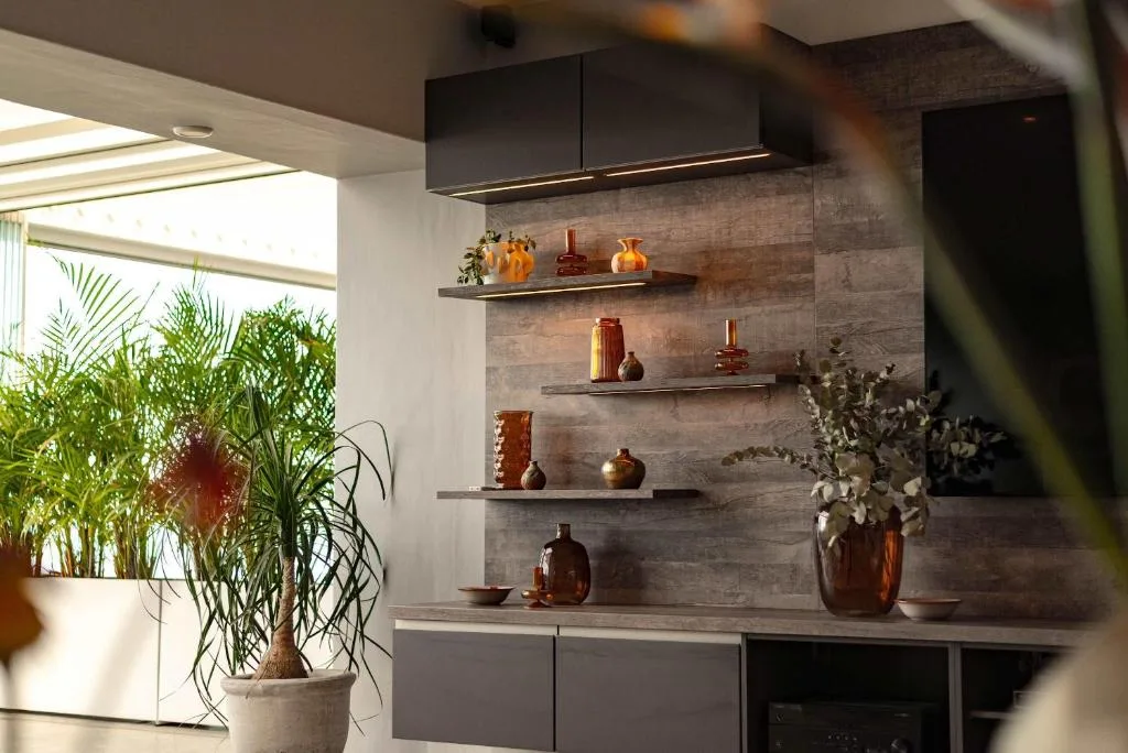 Modern kitchen shelving with decorative amber vessels and potted plants
