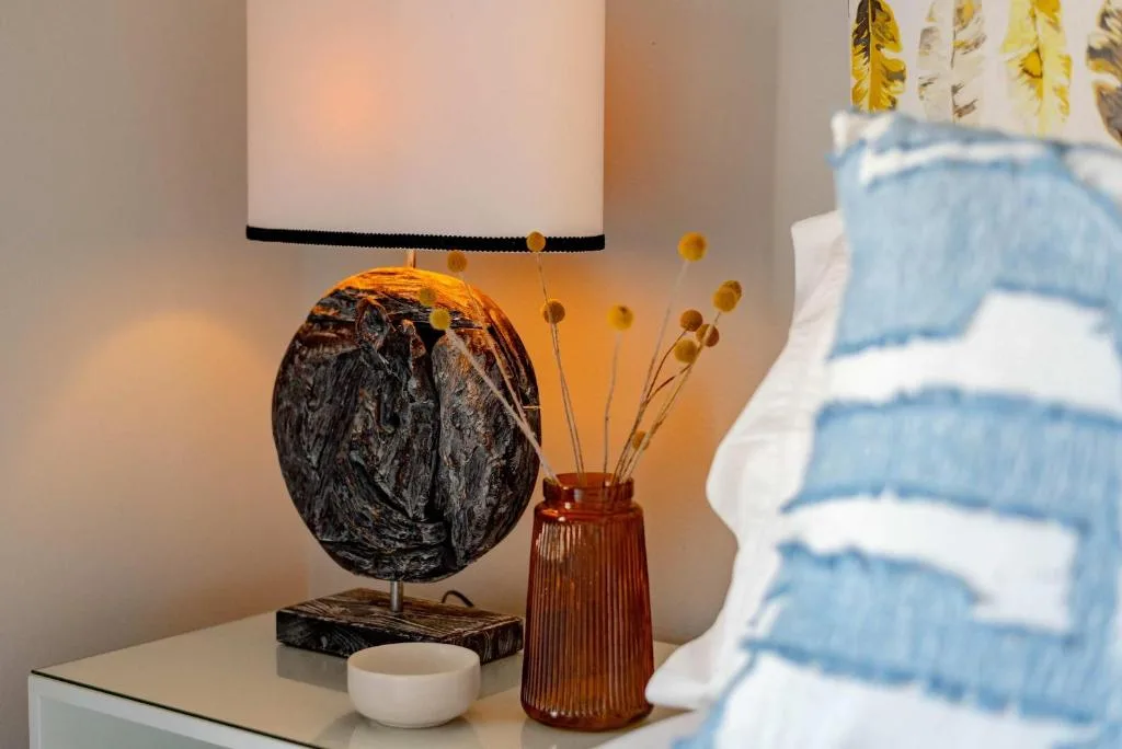 Decorative table lamp with textured black sphere base beside dried flower arrangement