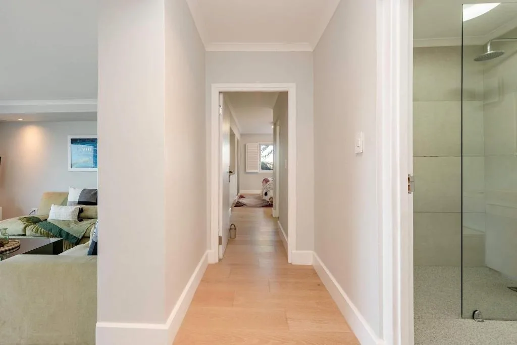 Bright hallway with wooden floors connecting bedroom and bathroom areas