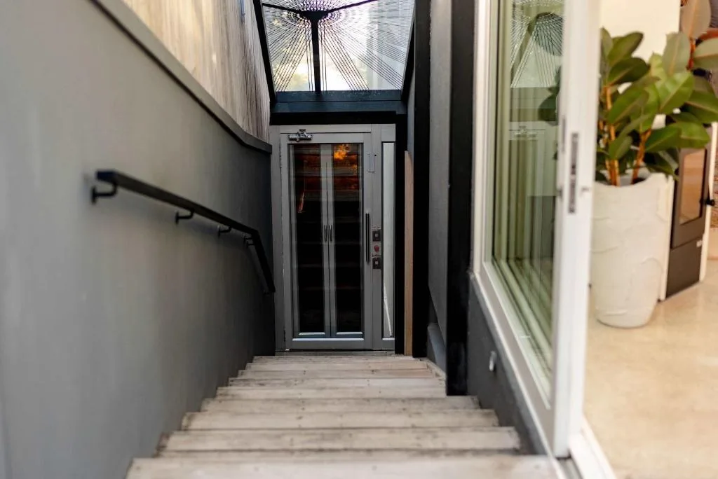 Modern entrance with dark frame door and potted plants lining the passage