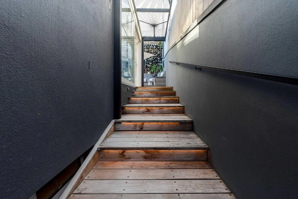 Modern wooden staircase leading to contemporary villa entrance with dark walls