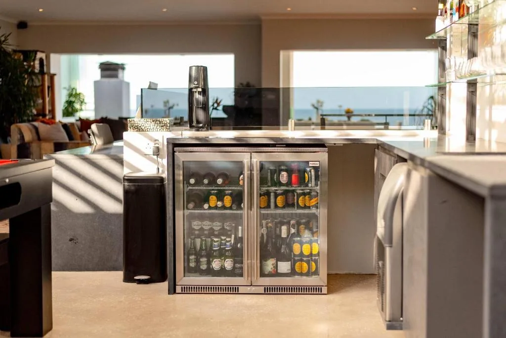 Modern kitchen with stainless steel appliances and beverage cooler overlooking ocean