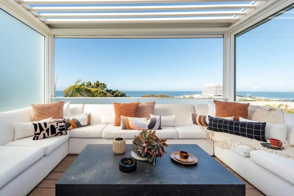 Modern white sectional sofa with ocean view through floor-to-ceiling windows