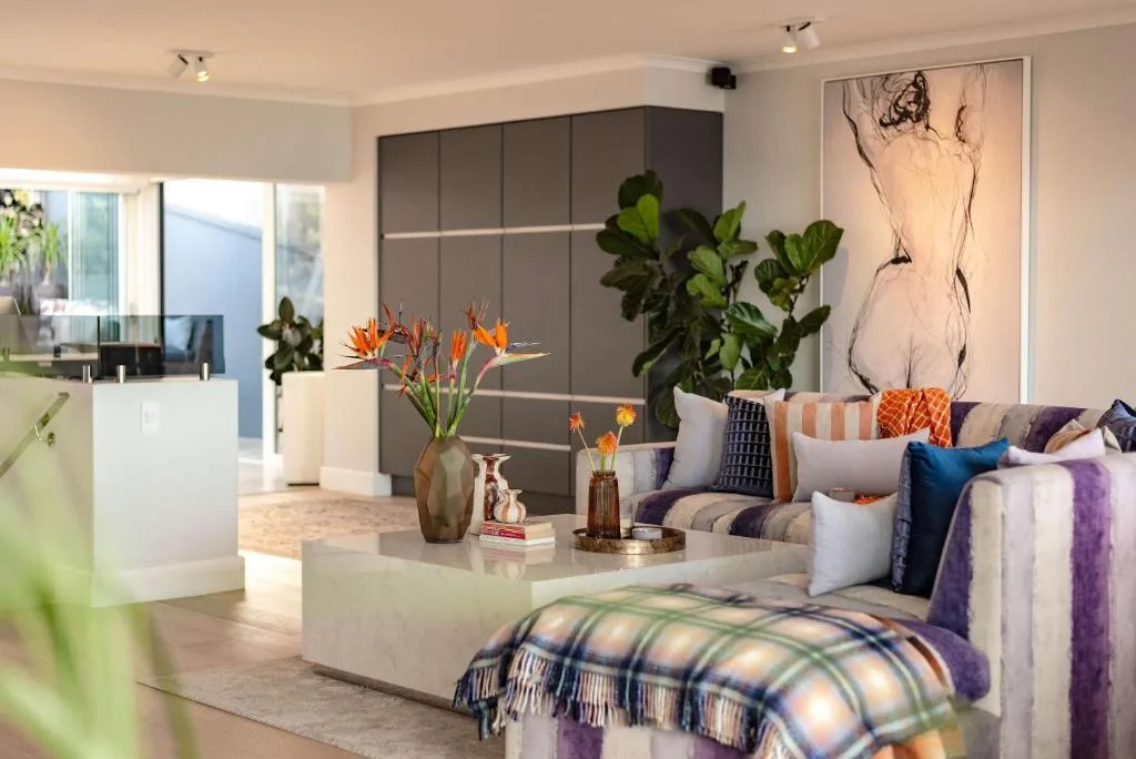 Modern lounge with striped sofa, colorful cushions, and potted plants