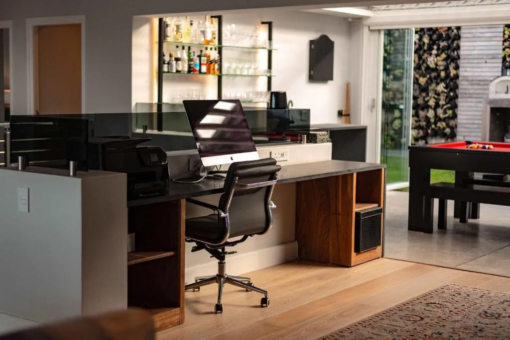 Modern lounge with desk workspace, bar area, and entertainment setup