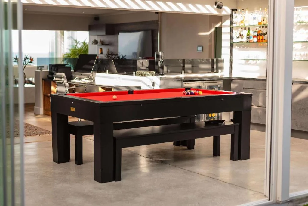 Modern lounge with pool table, ocean view through windows, and open-plan kitchen