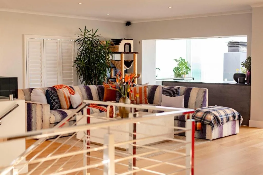 Modern lounge with striped sofa, colorful cushions, and indoor plants