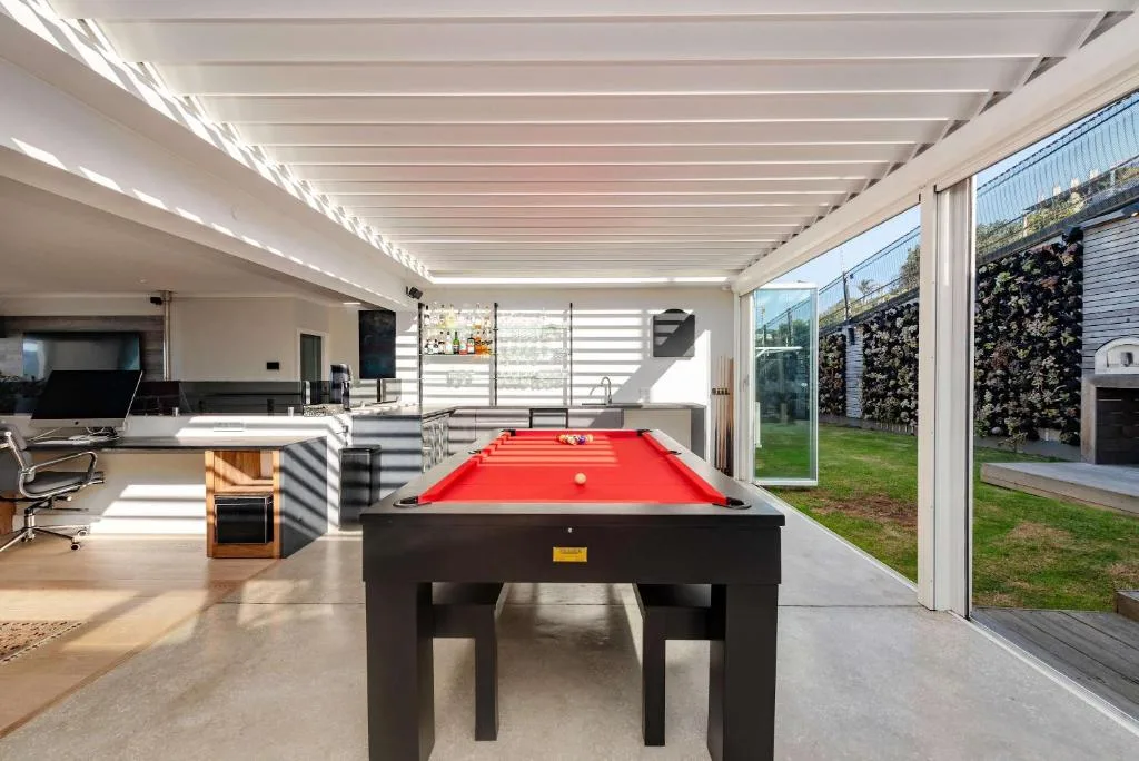 Modern open-plan lounge with pool table and garden views through glass doors