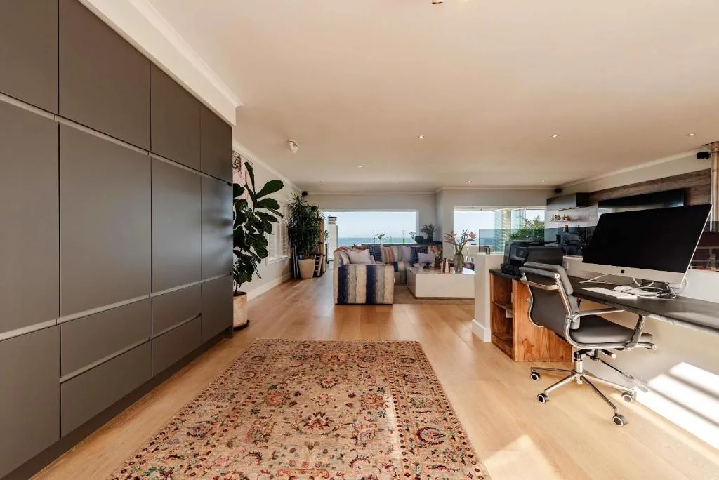 Modern open-plan lounge with striped armchairs, workspace, and ocean views