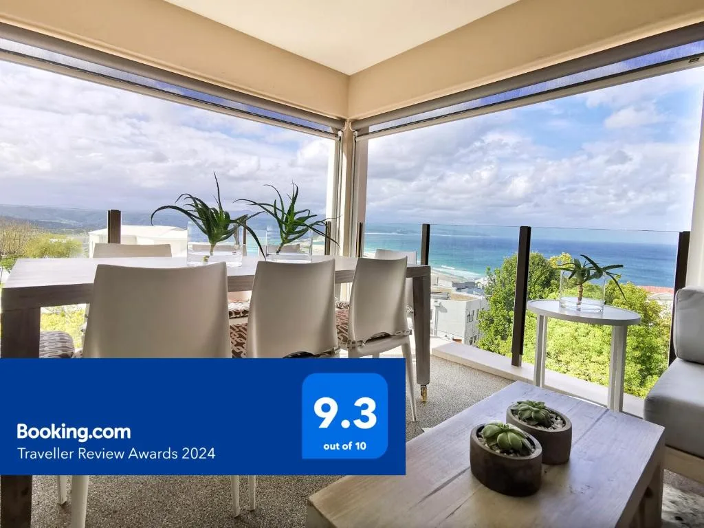Elevated deck with ocean views, dining furniture, and coastal landscape beyond