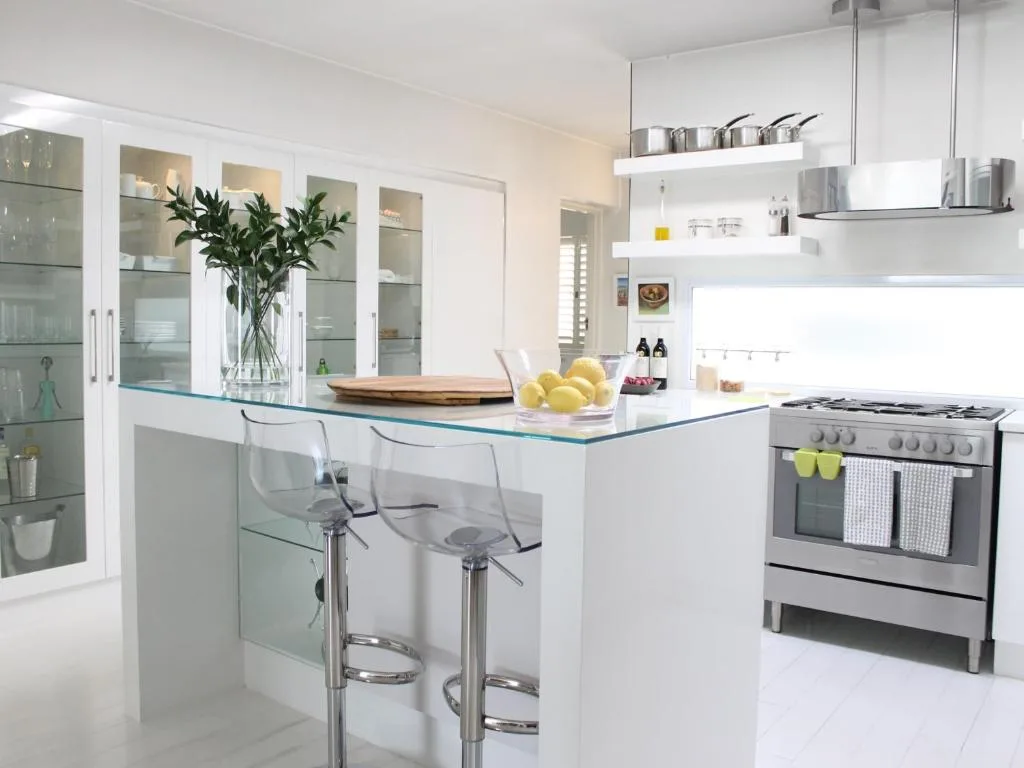 Modern white kitchen with island, stove, and glass-fronted cabinetry