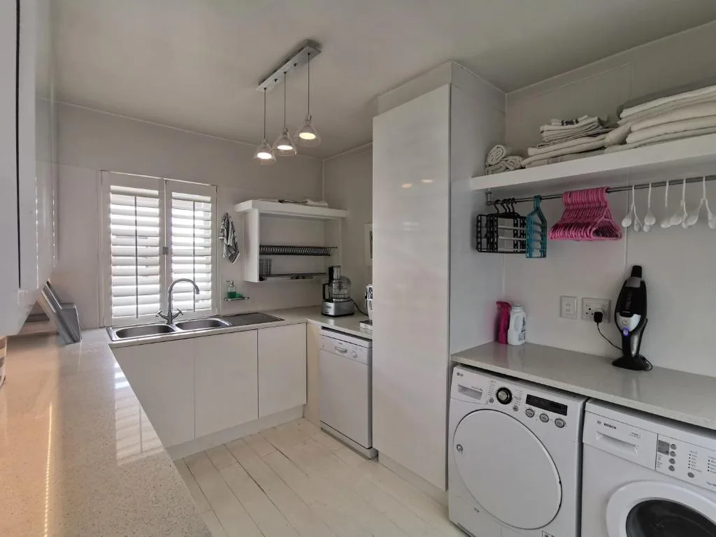 Modern white kitchen with island, sink, appliances, and laundry area