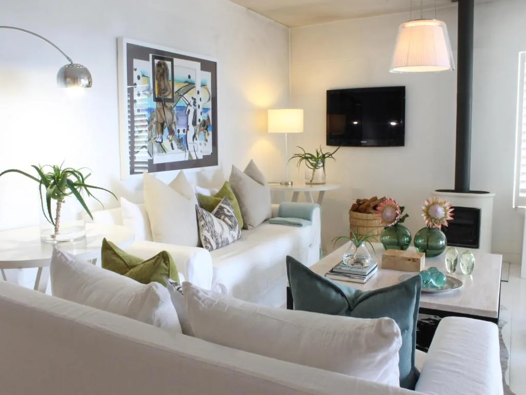 Bright lounge with white sofas, wall-mounted TV, and decorative accents
