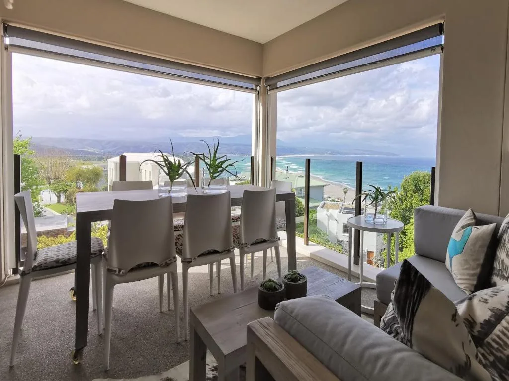 Panoramic ocean and mountain views from modern dining and lounge area with large windows