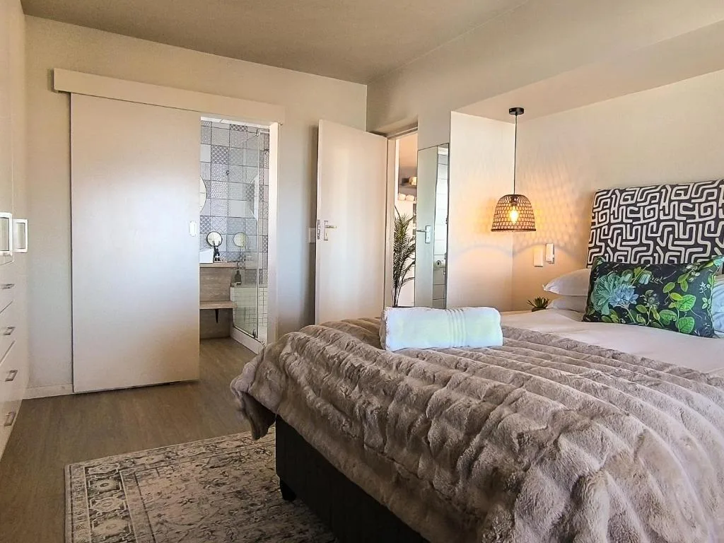 Bright bedroom with queen bed, ensuite bathroom visible through open door