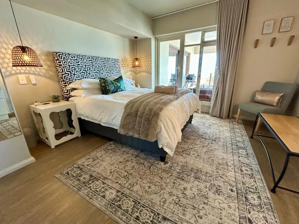 Modern bedroom with queen bed, patterned headboard, pendant lighting, and garden view doors