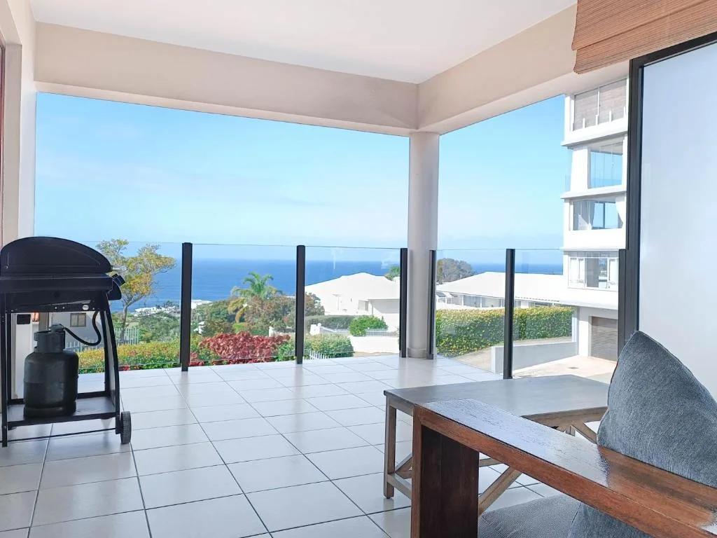 Spacious outdoor patio with ocean views, braai grill, and coastal landscape beyond
