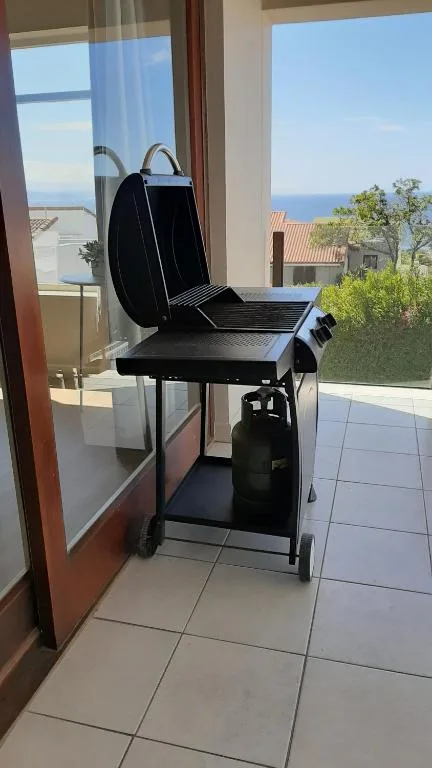 Portable braai grill on tiled deck with ocean and mountain views