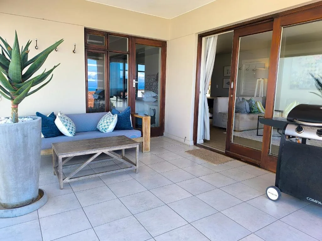 Covered patio with blue sofa, coffee table, and ocean views through glass doors