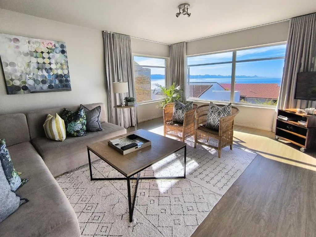Bright lounge with gray sofa, coffee table, ocean and mountain views through windows