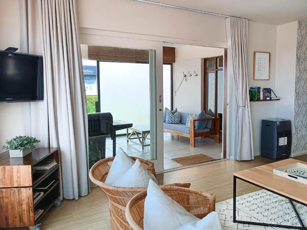 Open-plan lounge with wicker chairs, TV, and sliding doors to deck area