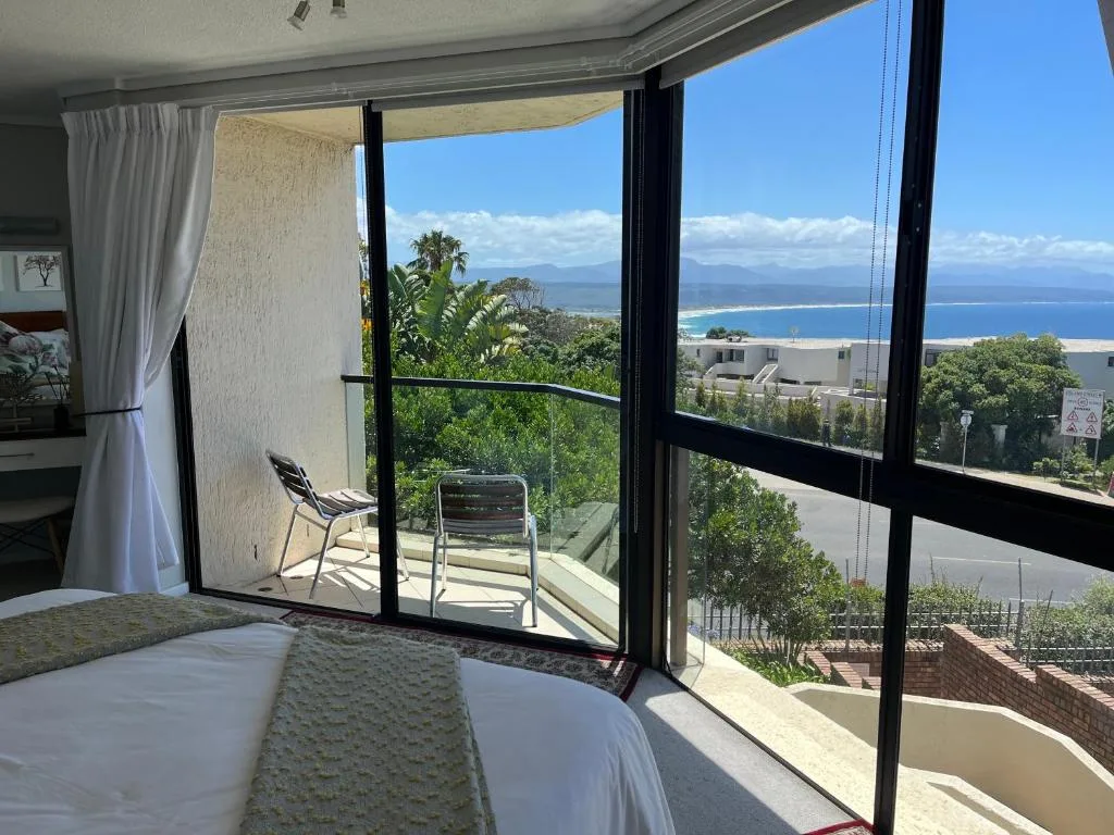 Bedroom with coastal ocean and mountain views through large windows