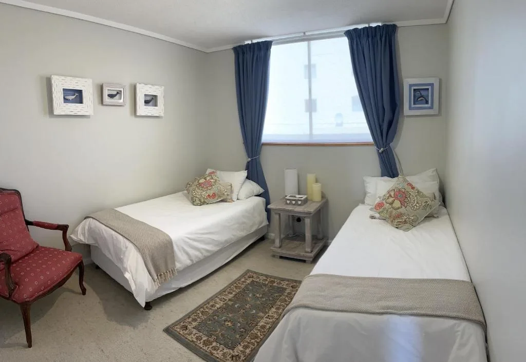 Twin bedroom with two single beds, navy curtains, and coastal artwork