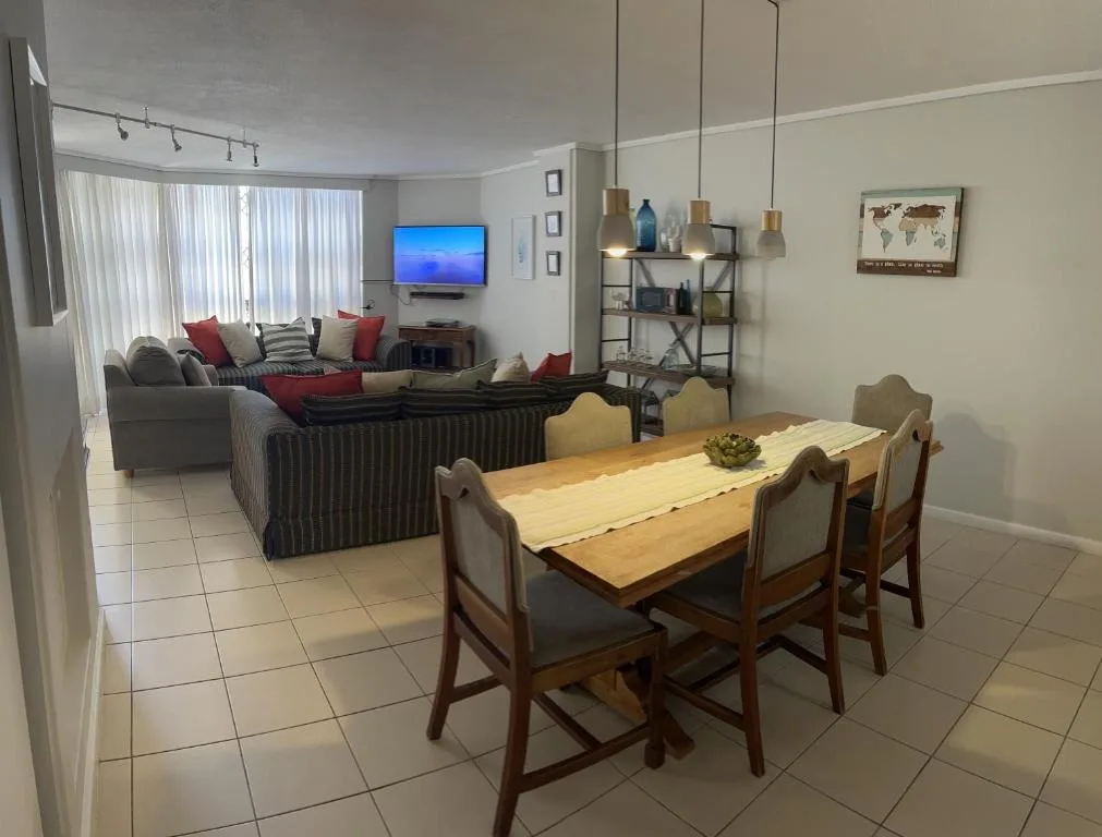 Wooden dining table with chairs, open-plan lounge beyond with sofa