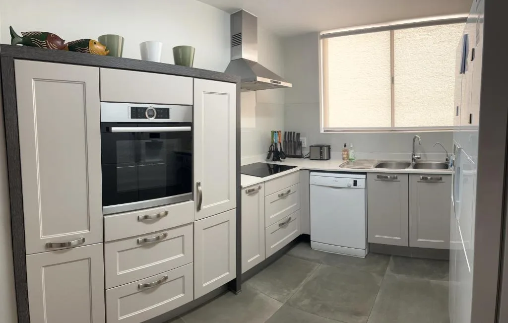 Modern kitchen with white cabinetry, stainless steel appliances, and black countertops