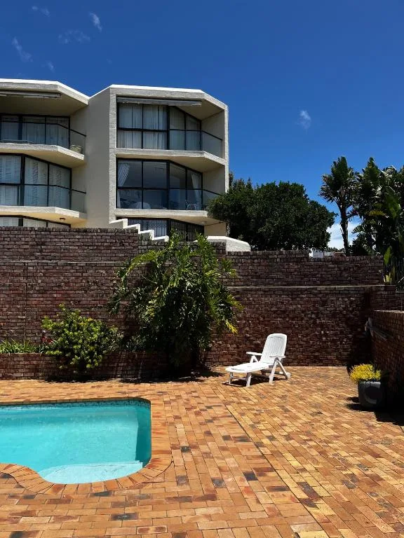 Turquoise swimming pool on brick patio with modern building facade