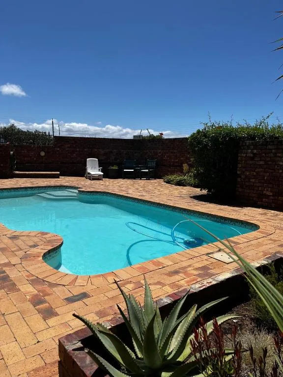 Turquoise swimming pool with brick paving and garden surroundings