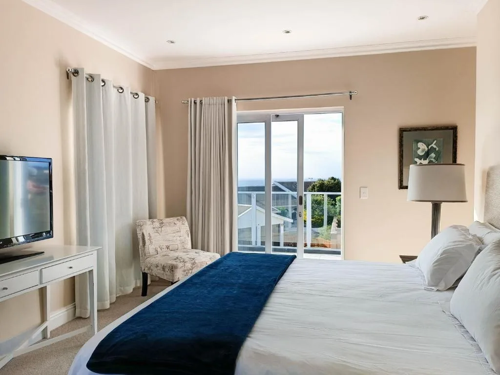Spacious bedroom with ocean views through glass doors and balcony access