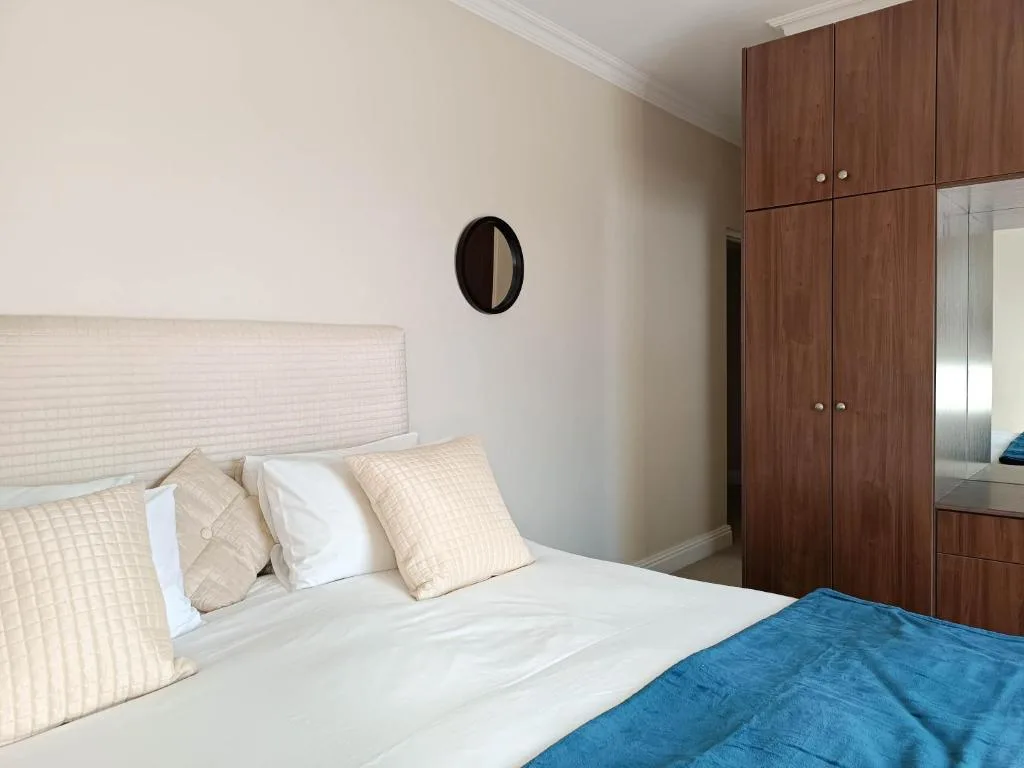 Modern bedroom with queen bed, wooden wardrobe, and neutral bedding