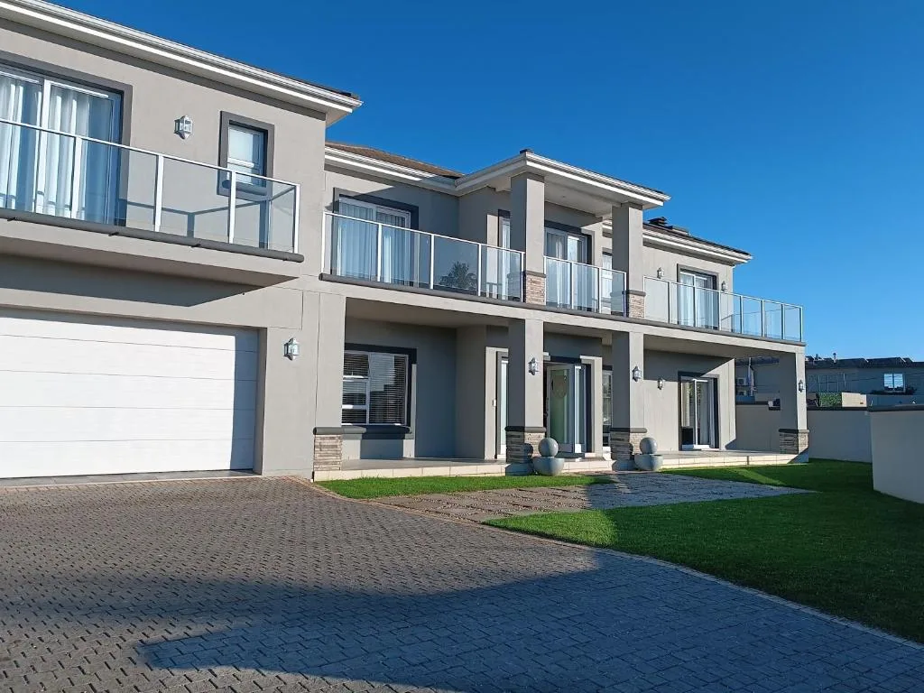 Modern two-story house with white garage, balconies, and manicured lawn
