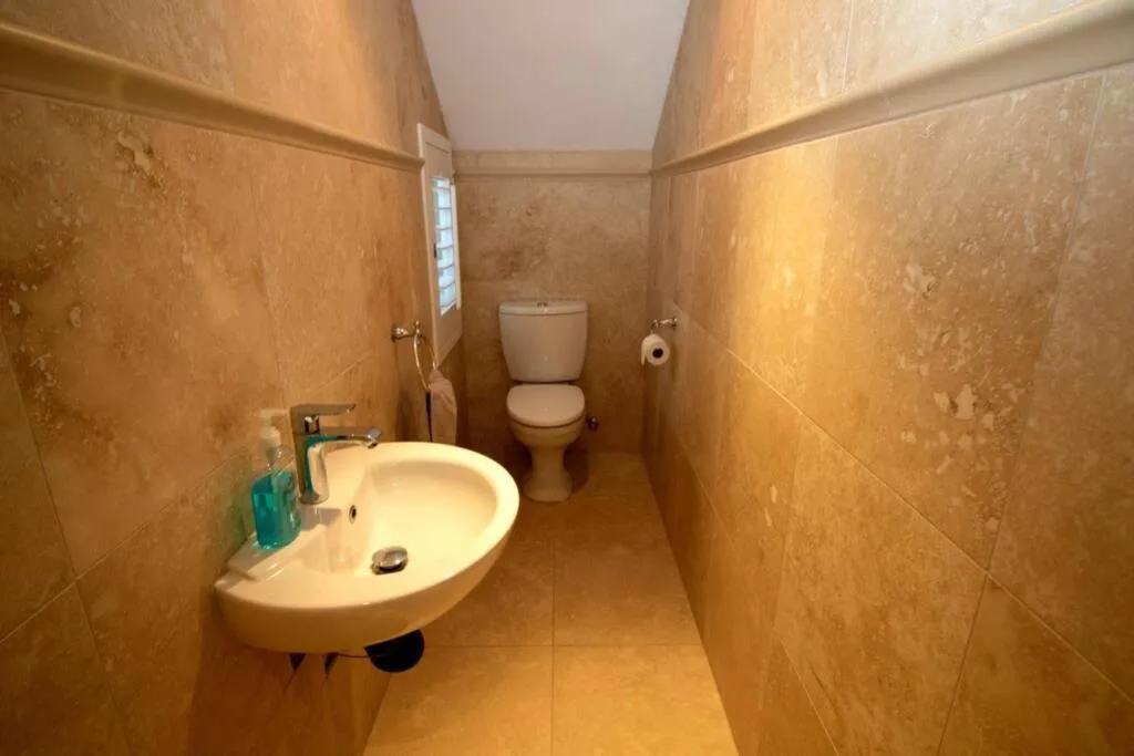 Bathroom with round sink, toilet, and terracotta tile walls