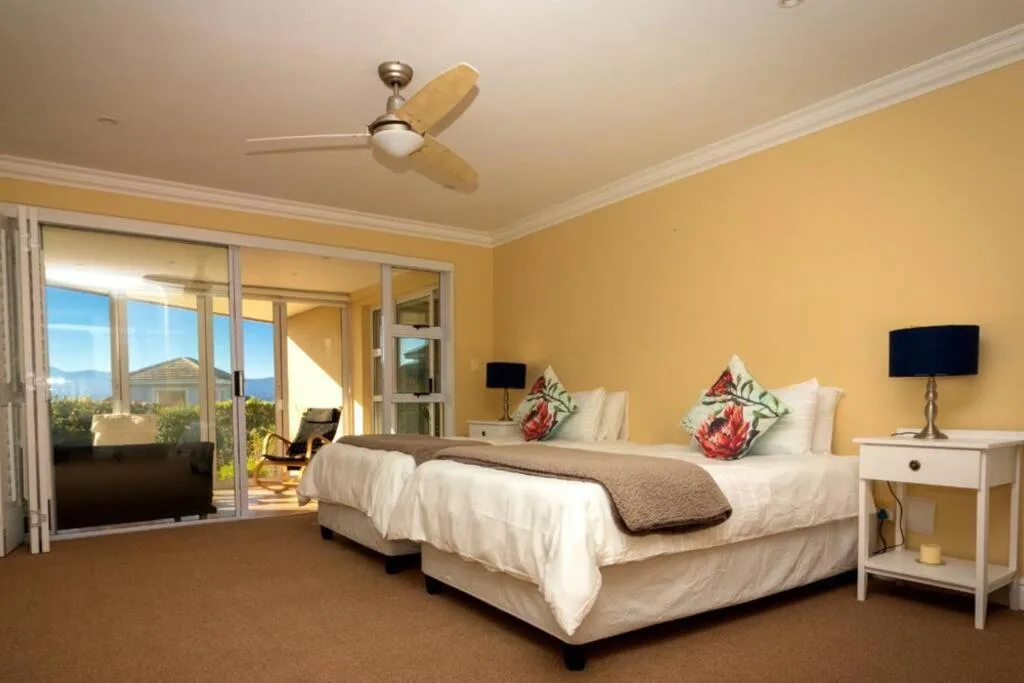 Spacious bedroom with twin beds, yellow walls, and mountain views through glass doors