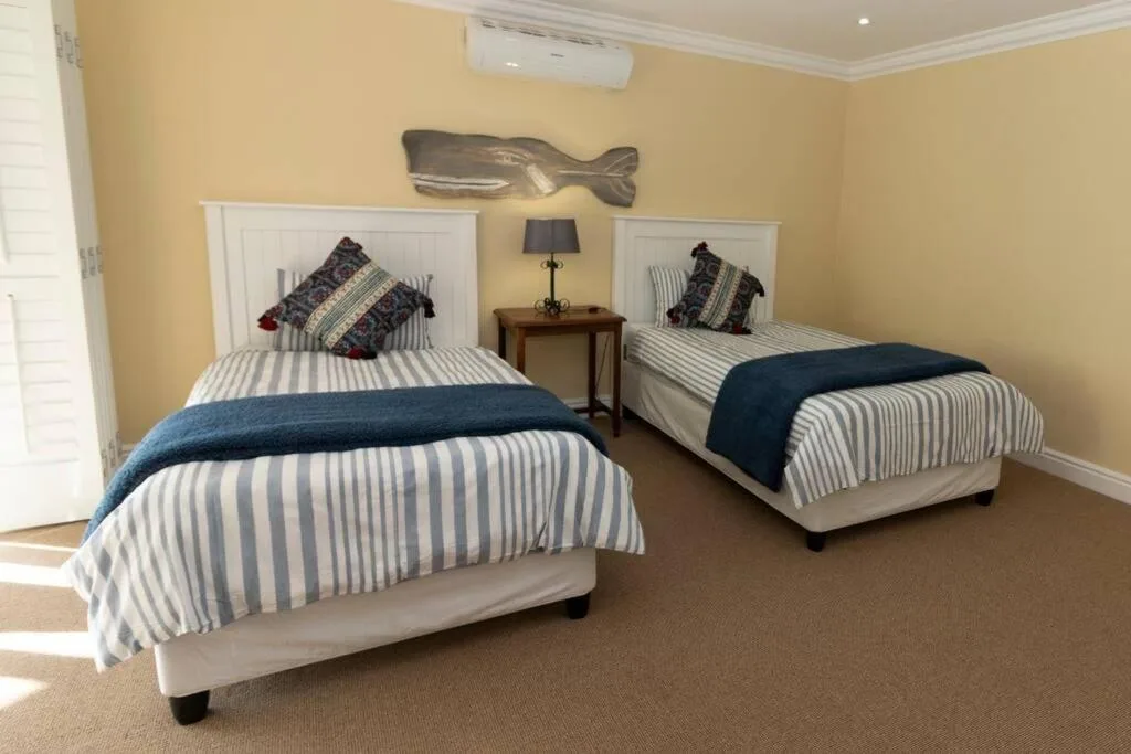 Twin bedroom with striped bedding, nautical decor, and shared bedside table