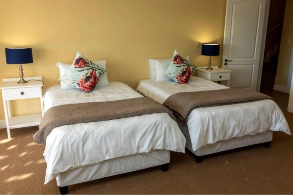 Twin bedroom with white bedding, floral pillows, and bedside lamps